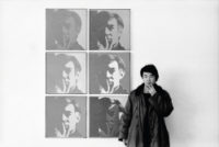 Artist Ai Weiwei stands in front of six portraits of Andy Warhol and mimics his pensive pose.