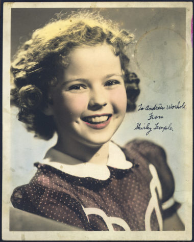 Early photograph of Shirley Temple as a child. She is smiling, has short, curly hair, and is wearing a dress with a white collar. Written on the photograph is "To Andy Warhola from Shirley Temple."