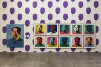 A wall on the fourth floor of The Andy Warhol Museum. The wallpaper is a white background with many reproduction images of Mao Zedong drawn by Andy Warhol. The drawings on the wallpaper are black outline of Mao's profile. His face is painted in purple. The artworks on the wall are eleven various screen prints by Andy Warhol of the same photograph of Mao with various colors of paint used to cover various sections of Mao's face, clothing and the background.