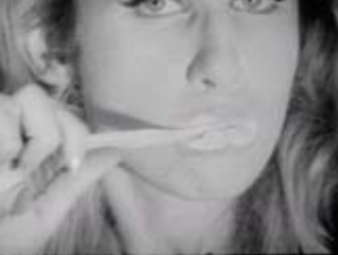 A still from one of Andy Warhol's black and white film screen tests in which Jane Holzer is brushing her teeth.