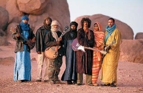 A group of people poses together in a desert.