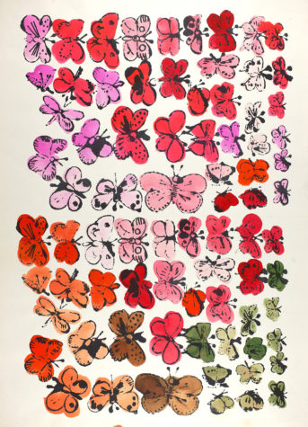 Dozens of butterflies of various hues and sizes are stamped to fill most of a manila sheet of paper.