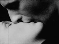 A black and white film still close up of a man and woman kissing.