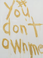 A painting of the words "#Youdon'townme" in yellow paint on a white canvas.