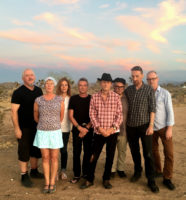 A group of eight people stand together looking at the camera.