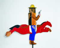 3D sculpture of John Wayne in a cowboy outfit holding a gun while riding a red horse.