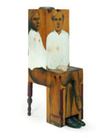 3-D sculpture of Andy Warhol sitting in a chair.