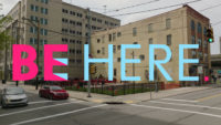 Video still that is a photo of The Warhol greenspace with "Be Here" in text overlay.