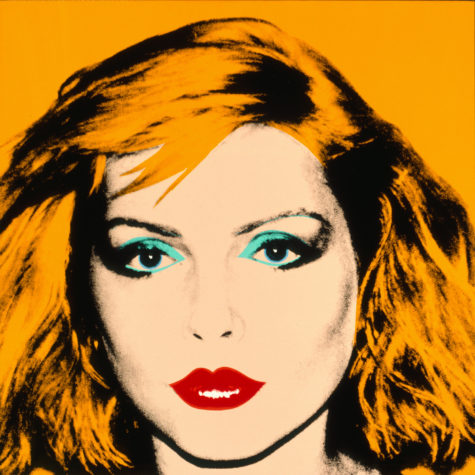 A screenprint on a yellow background of a closeup of Debbie Harry. Her hair matches the background color and she has blue eyeshadow and red lipstick.
