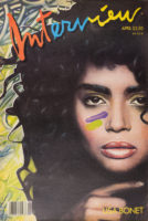 Front cover of Interview magazine that has a color artwork of a closeup of Lisa Bonet on a black and yellow artistic background. She has long, dark hair and brown eyes and is looking forward. She has yellow eyeshadow and red lipstick on and a purple and green paint line is on her right cheek. Overlaid on the artwork it says, "Interview" in red, blue, and yellow with "Interview" in black as a drop shadow and "April $2.50" in yellow underneath. In the bottom right, it says "Lisa Bonet" in all caps in yellow. There is a UPC symbol on the bottom left corner.