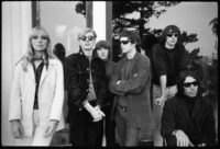 Black and white photograph of the Velvet Underground & Nico with Andy Warhol standing outside in front of a corner of a building.