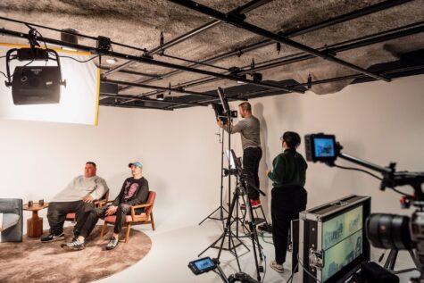 Staff of The Warhol Creative are filming people sitting on chairs inside their studio with lights and video camera equipment.