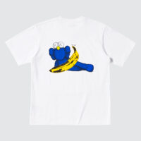 White T-shirt featuring a playful graphic of a blue cartoon-like figure by the artist KAWS lying with a banana by Andy Warhol.