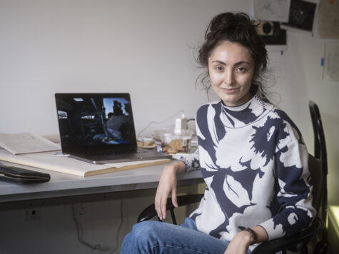A woman sits at a desk with a laptop on it looking behind her.